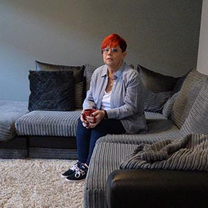 Sue sitting on her sofa in lounge