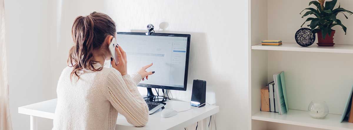 lady at desk on phone looking at computer monitor